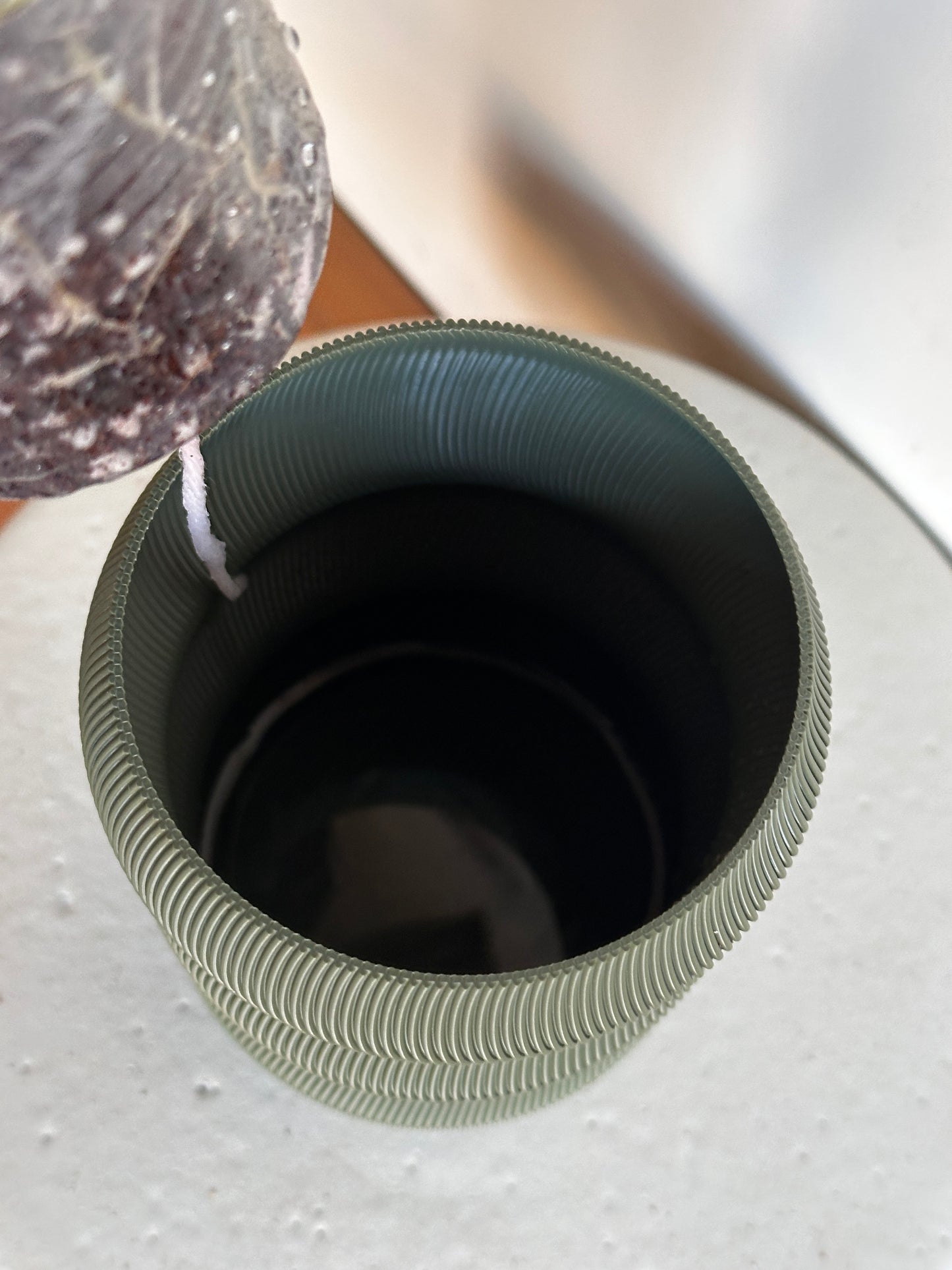 Close-up of a textured green container with a black interior on a light gray background